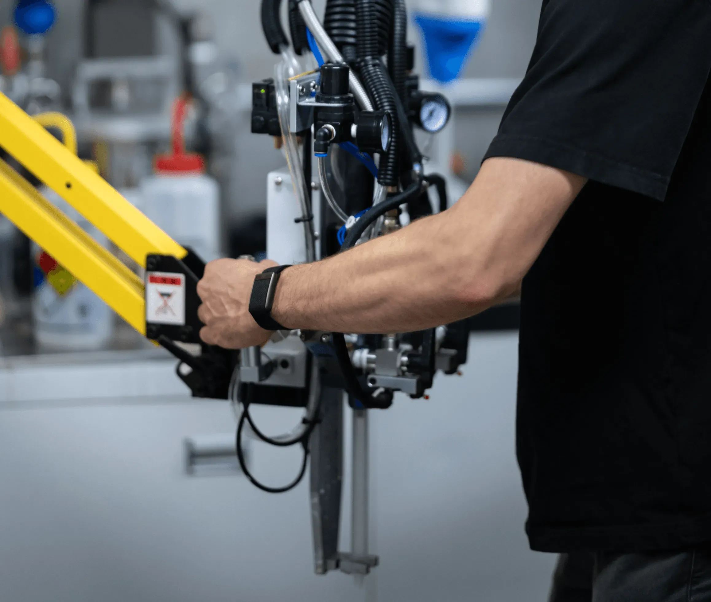 Estes engineer guiding a pneumatic tool on a yellow articulated arm in the lab